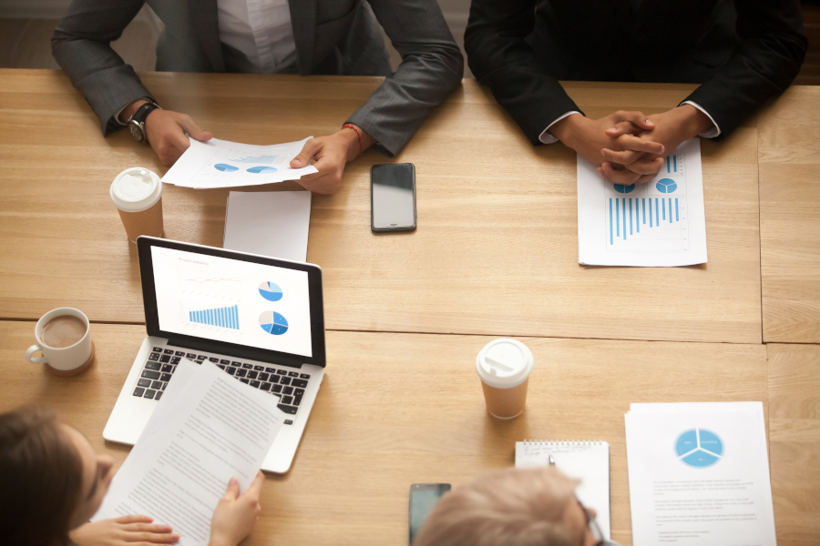 Business team brainstorming analyzing statistics report at meeti Business team brainstorm on new marketing plan analyzing statistics at group meeting, businesspeople working together on project report with financial results, teamwork concept, top view from above